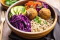 a falafel bowl with brown rice and purple cabbage served in a bamboo bowl