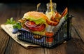 Falafel burger with addition of lettuce, tomato, onion, pickle cucumbers, spicy aromatic sauce and herbs on a wooden rustic table.