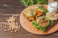 Rye bread sandwiches with chickpea cutlets and vegetable salad. On a wooden board with sauce. And chickpeas on the table