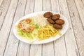 Falafel menu with balls, white rice, french fries, lettuce salad and tomato slices with white onion strips on light wooden Royalty Free Stock Photo