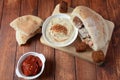 Falafel in pita bread with vegetable salad, harissa sauce, humus, tahini on wooden background.