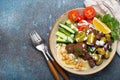 Falafel salad bowl with hummus, vegetables, olives, herbs and yogurt sauce. Vegan lunch plate top view on rustic stone Royalty Free Stock Photo