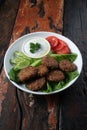 Falafel, vegan roasted chickpeas patties with garlic yogurt sauce on rustic wooden table