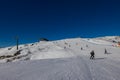 Ski slope with skier under blue sky. People drive down the snowy mountains on skis. Group of
