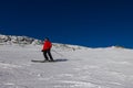 Ski slope with skier under blue sky. People drive down the snowy mountains on skis. Group of