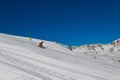 Ski slope with skier under blue sky. People drive down the snowy mountains on skis. Group of