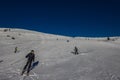 Falcade, Italy - February 15, 2023: Ski slope with skier under blue sky. People drive down the snowy mountains on skis. Group of