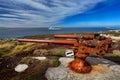 Falklands War, rocky coast with old rusty cannon. Corroded artillery gun from Falklands Conflict in nature habitat. Blue sky lands