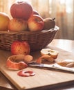 Fall apple composition, wicker basket filled with red and yellow apples, peeled apple it front