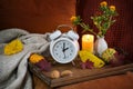 Fall back in autumn after daylight saving time, white alarm clock on a wooden tray with candle and warm colored fall decoration on Royalty Free Stock Photo