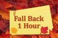 Fall Back 1 Hour with fall leaves on reminder index card on wood for DST Royalty Free Stock Photo