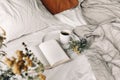 Fall breakfast still life. Cup of coffee, open book and tansy flowers on white linen background. Blurred floral