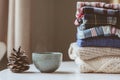 Fall casual woman fashion clothes set. Stack of plaid shirts and knitted sweaters with pine cone and cup of tea