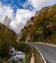 Fall color forest and rocky cliffs with a winding mountain road next to a small river Royalty Free Stock Photo