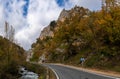 Fall color forest and rocky cliffs with a winding mountain road next to a small river Royalty Free Stock Photo