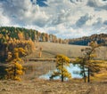 Fall colored larch trees are reflected in a beautiful mountain l Royalty Free Stock Photo
