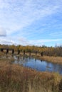 View of abandoned bridge in the distance amongst fall colors are reflected in a river in Hayward, Wisconsin