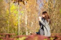 Fall concept - beautiful woman drinking coffee in autumn park under fall foliage Royalty Free Stock Photo