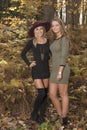 Two beautiful female friends pose in dresses in autumn woods - fashion