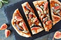 Fall flat bread with figs, caramelized onions, blue cheese and rosemary, top view close up on slate