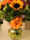 fall flower arrangement in glass vase, sunflowers, roses, purple flowers, green leaves, Royalty Free Stock Photo
