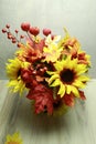 fall flower arrangement of red and orange leaves, sunflowers, peach flowers, red berries