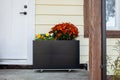 Fall flowers decorate the front door stoop of a house.