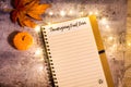 Thanksgiving Food Drive list concept on notebook surrounded with bright leaves and decorative lights, flat lay