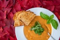 Fall harvest bisque soup of pureed squash and other fall vegetables, in a white bowl, toasted bread, basil, and spoon, background Royalty Free Stock Photo