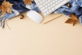 Top view arrangement of keyboard, pen, comfortable plaid, computer mouse, maple leaves on pastel beige background Royalty Free Stock Photo