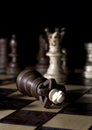 Fall of the king after checkmate at the end of a game on top of a chess board in front of a dark background Royalty Free Stock Photo