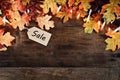 Fall Leaves and Sales Tag over Wooden Background Royalty Free Stock Photo