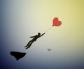 Fall in love concept, boy silhouette holds the red heart shaped balloon and flying up to sun, dreamer concept, shadow