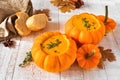 Fall pumpkin soup in pumpkin bowls. Table scene against rustic white wood. Royalty Free Stock Photo