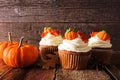 Fall pumpkin spice cupcakes with creamy frosting close up against wood