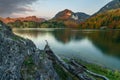 Fall scene taken at sunset of a calm lake surrounded by mountains and a deciduous forest with strong fall colors. The last reddish Royalty Free Stock Photo