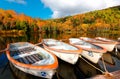 Fall scenery of row boats parking at a wooden dock by Lake Kido Ike & colorful forests on the hillside reflected in the water