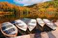 Fall scenery of row boats parking at a wooden dock by Lake Kido Ike & colorful forests on the hillside reflected in the water Royalty Free Stock Photo