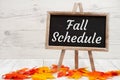 Fall Schedule sign on standing chalkboard on wood with fall leaves Royalty Free Stock Photo