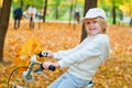 Fall season. Cute blond little caucasian girl riding a bike with yellow autumn maple leaves in a park. Happy childhood Royalty Free Stock Photo