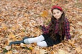 fall season fashion. teen girl in school uniform sit on autumn leaves. smiling child Royalty Free Stock Photo