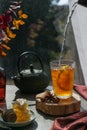 Fall season steaming hot tea with lemon, autumn leaves, honeycomb, wooden