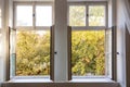 Fall season. Trees with autumn leaves out of two open white wooden windows.