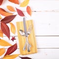 Fall Table Place Setting Invite Card with Brown and Gold Leaves, Silverware, and Napkin Flat Lay on White Shiplap boards backgrou