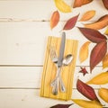 Fall Table Place Setting Invite Card with Brown and Gold Leaves, Silverware, and Napkin Flat Lay on White Shiplap boards backgrou