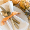 Fall Thanksgiving or Halloween Table Place Setting and pumpkins in Gold tones. Square with warm natural lighting from above lookin