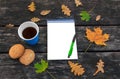 Fallen autumn leaves on the old wooden background, hot cup of coffee, homemade oatmeal cookies, notepad, pen. Autumn time. Royalty Free Stock Photo