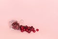 Fallen glass with scattered red ripe sweet cherry on pink background. Concept of fresh natural juice, smoothies, healthy eating or Royalty Free Stock Photo