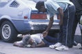 Fallen homeless man in city street getting help, Los Angeles, California