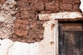 Fallen plaster on old adobe brick wall with wooden lintel in a rural house